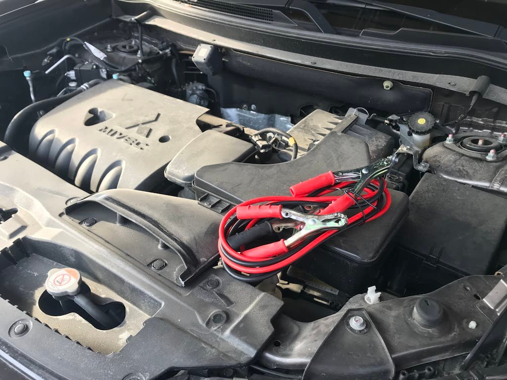 Detailed view of a car engine with red jumper cables, ideal for automotive themes.